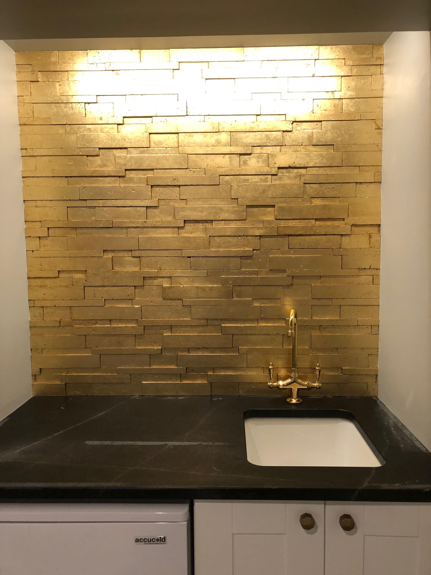 Finished gold stacked-stone accent wall above a wet bar counter