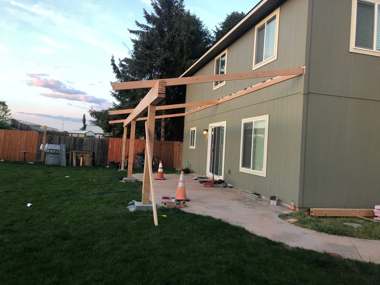 Covered patio roof framing in progress behind a two-story home