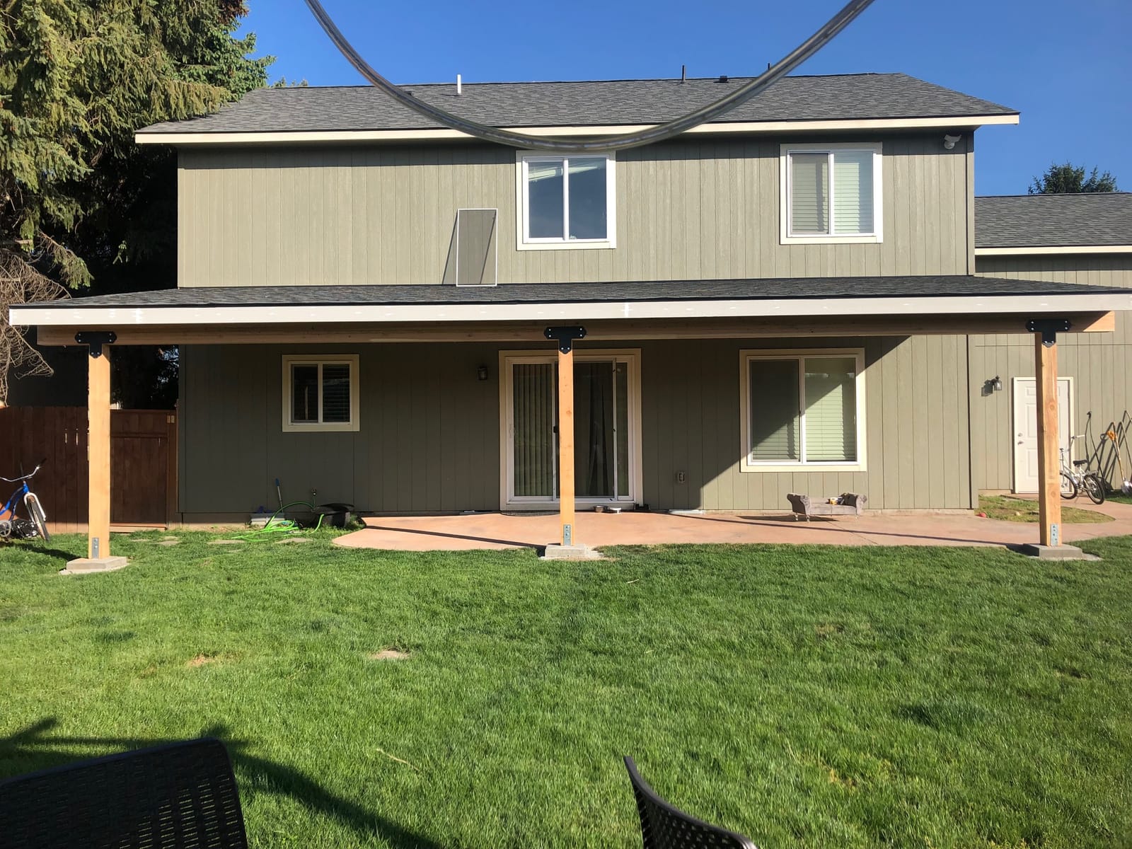 Completed covered patio with wood posts spanning the back of the home