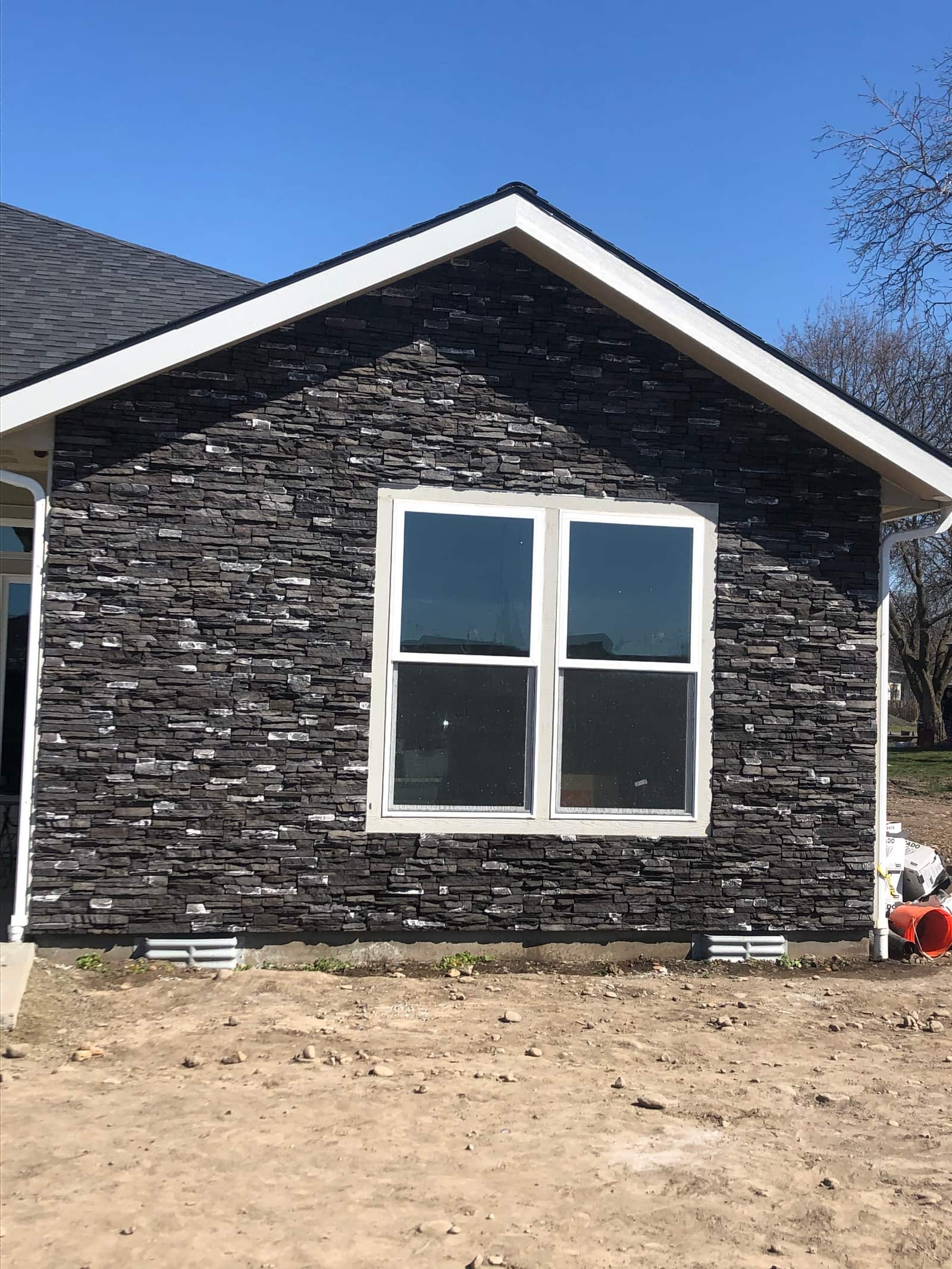 Gable wall finished in dark stacked-stone veneer