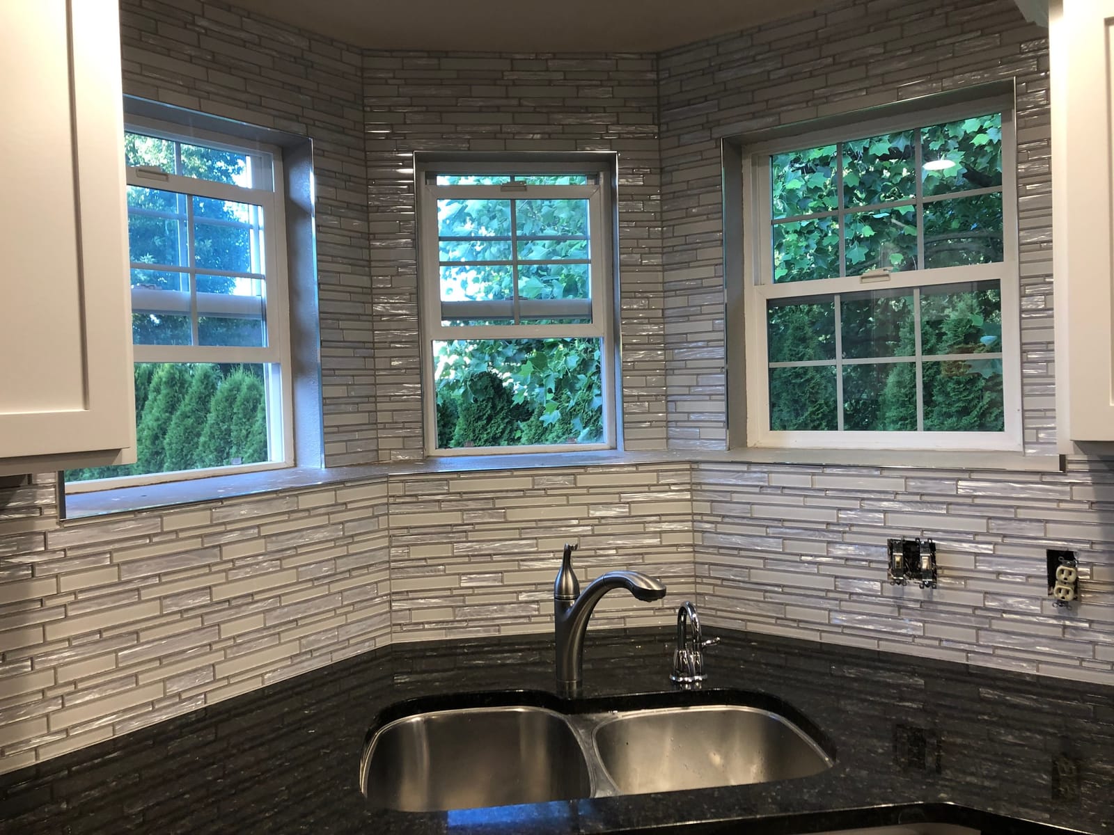 Kitchen corner with glass mosaic backsplash around bay windows