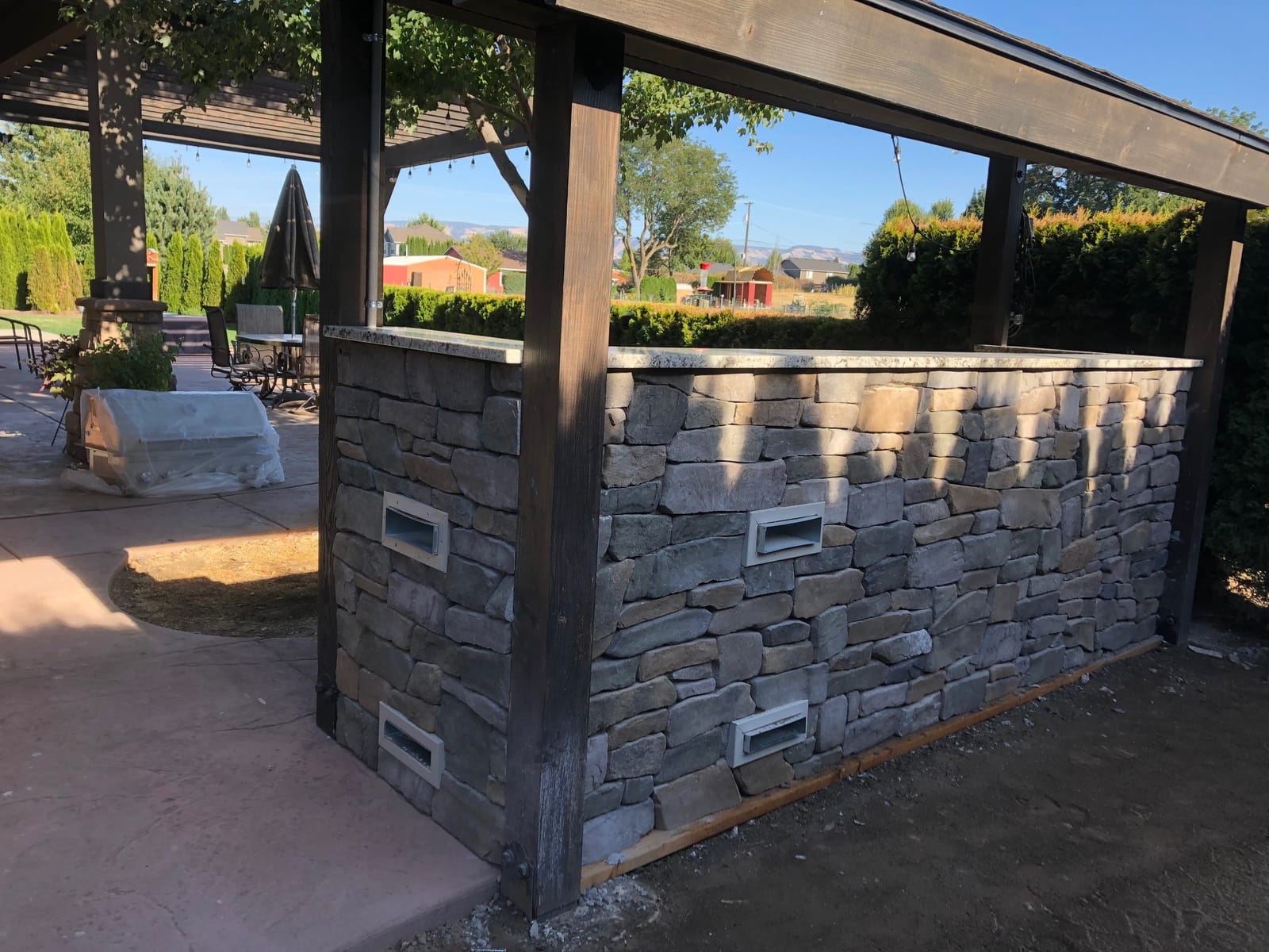 Finished outdoor bar clad in natural stone with a granite countertop