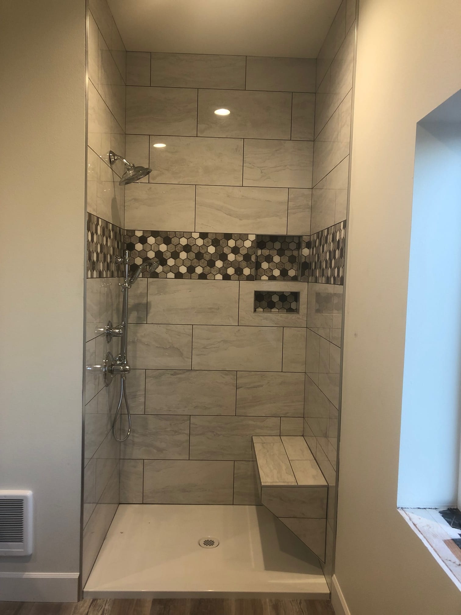 Shower with stone-look tile, hexagon accent band, and bench