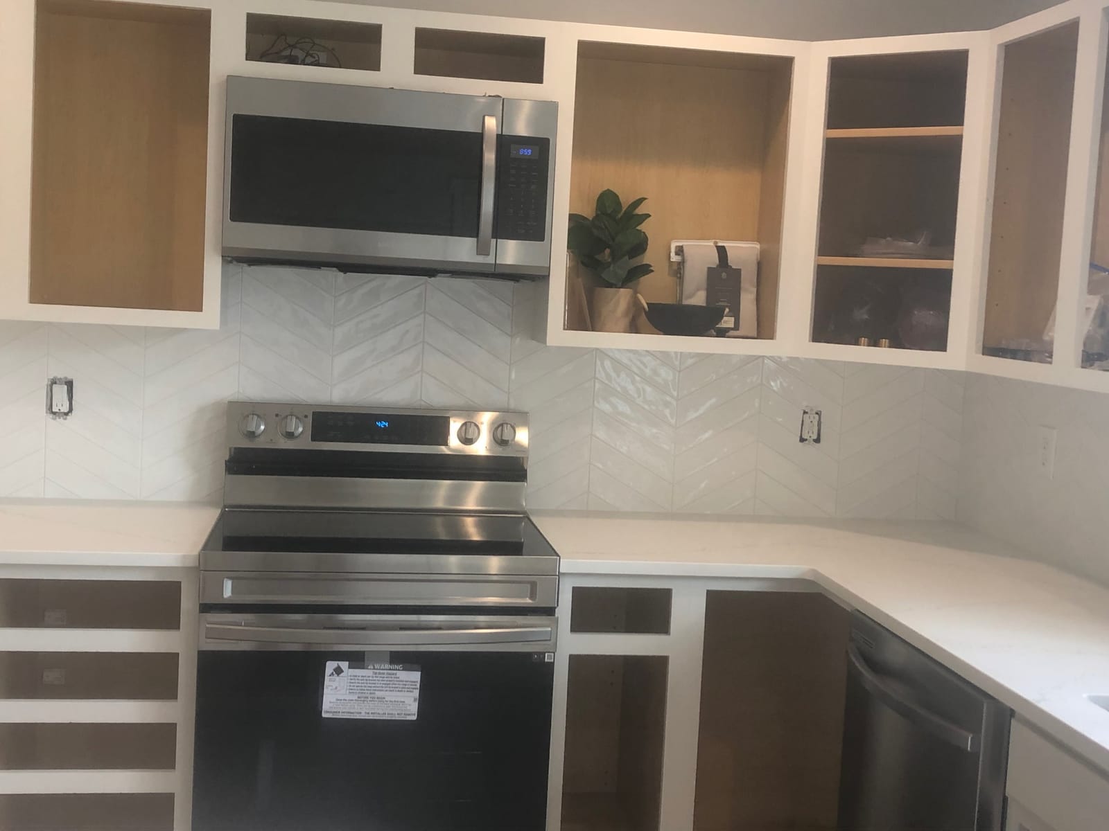 Kitchen with white cabinetry, chevron tile backsplash, and stainless appliances