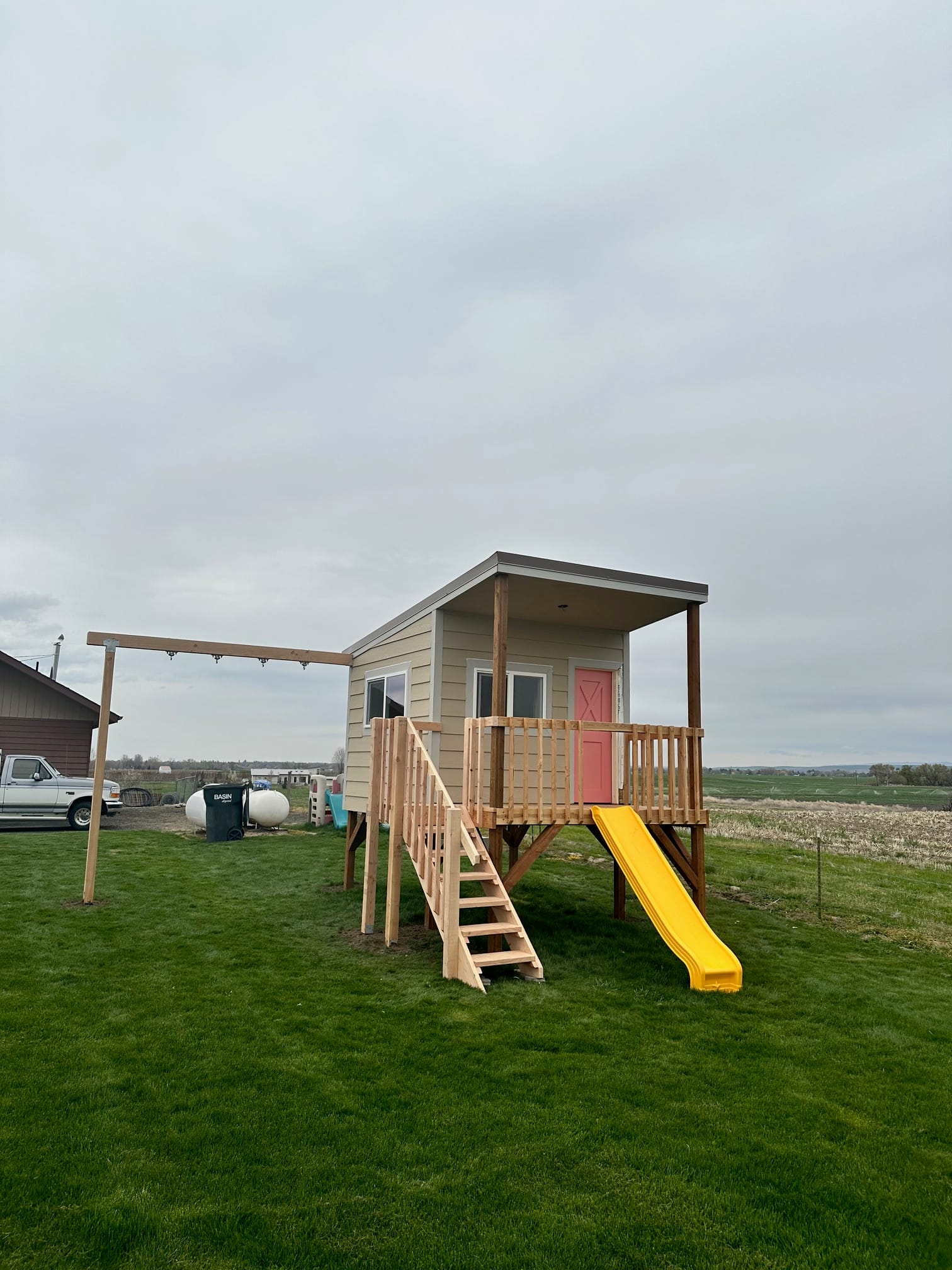 Finished elevated playhouse with stairs, slide, and swing beam