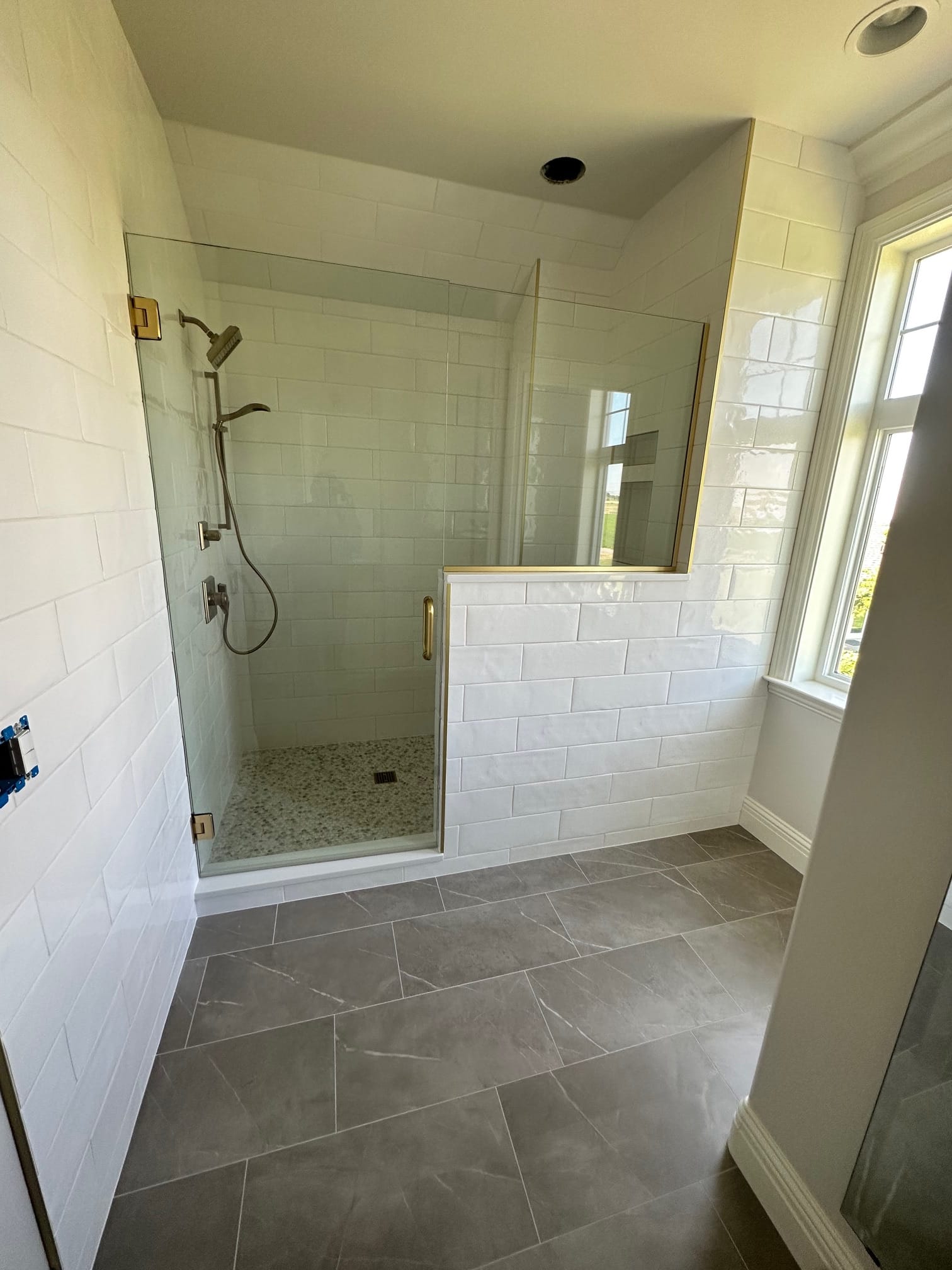 Walk-in shower with frameless glass, subway tile, and pebble floor