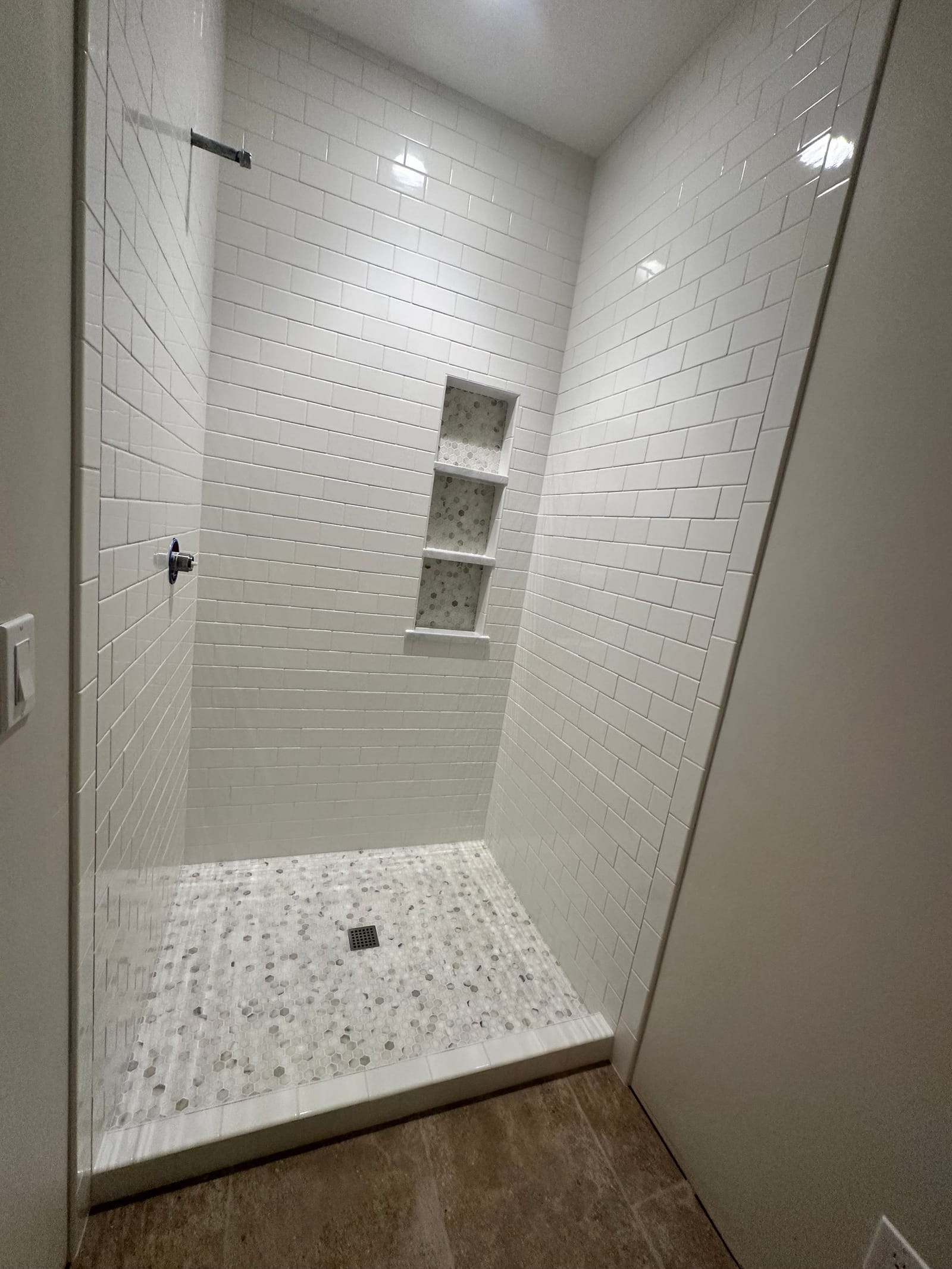 Finished walk-in shower with white subway tile and mosaic shower pan