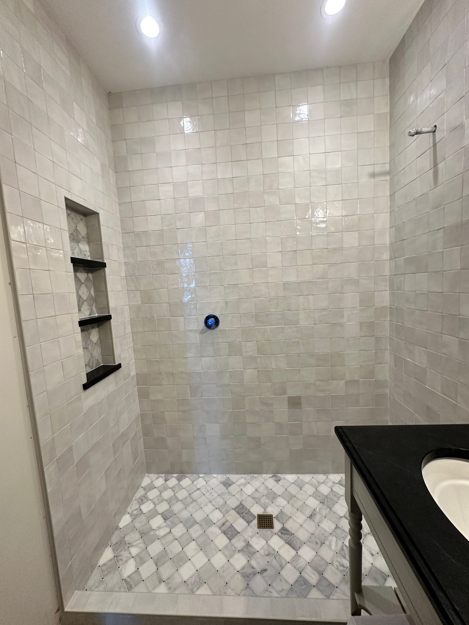 Finished shower with handmade-look square tile and marble mosaic floor