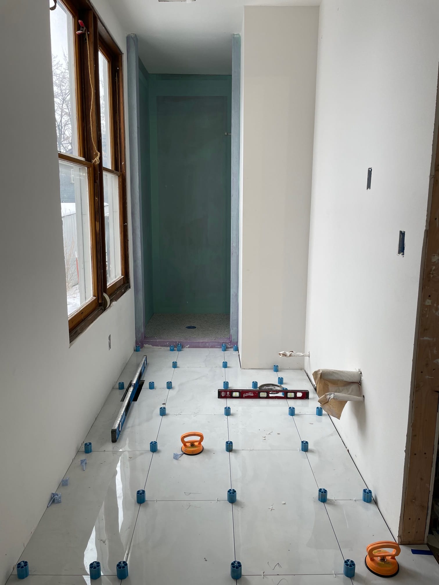 Bathroom floor tile being set with leveling spacers